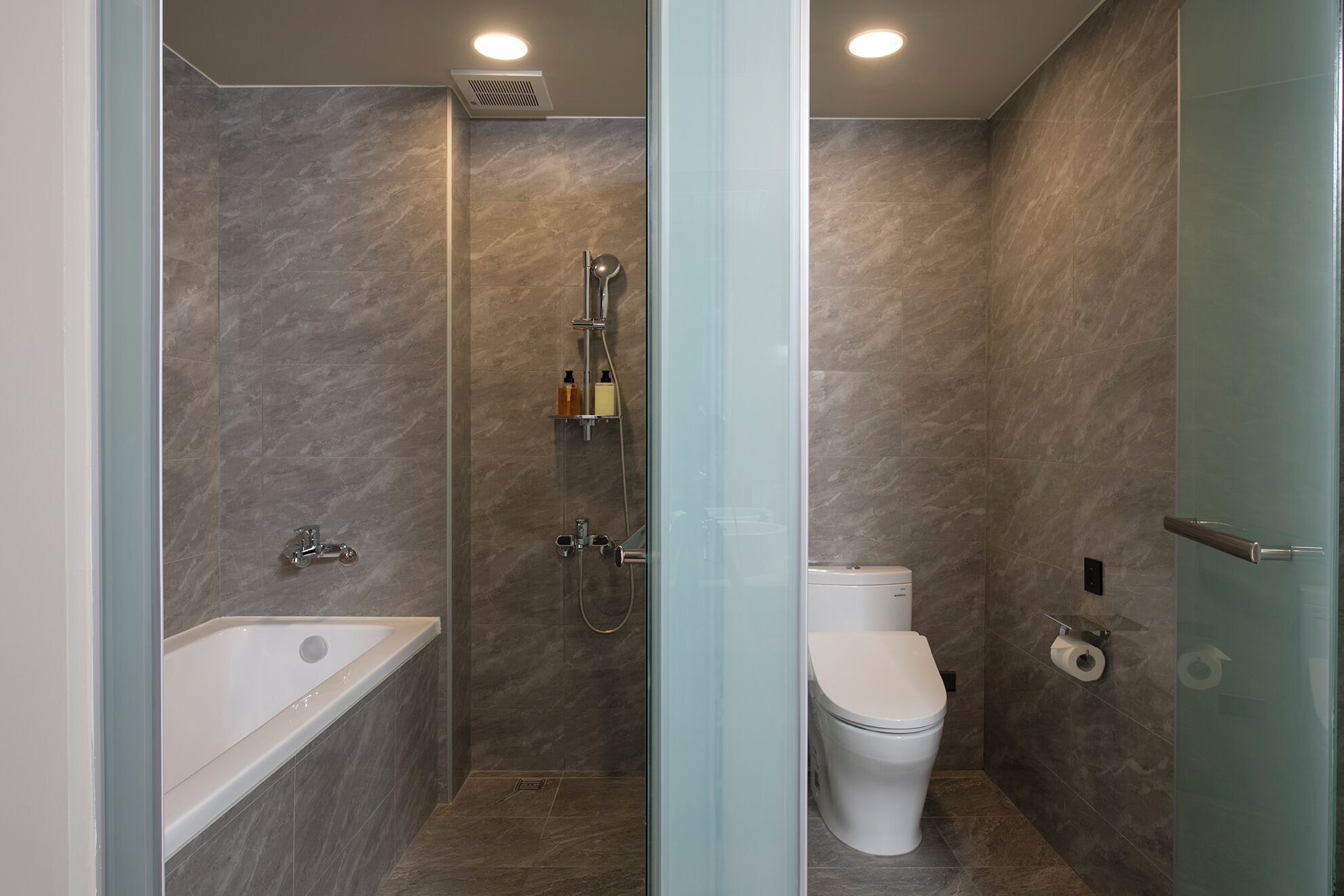 Un bagno moderno con doccia vetro, vasca da bagno e toilette.