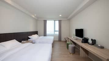 A hotel room with two beds, a TV, a desk with a coffee maker, and a trash can.