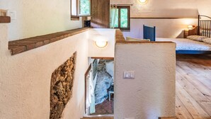 A staircase with a stone wall, wooden steps, and a view into a room with a bed and a window. - La casa del Fiume by Interhome (Rialto)