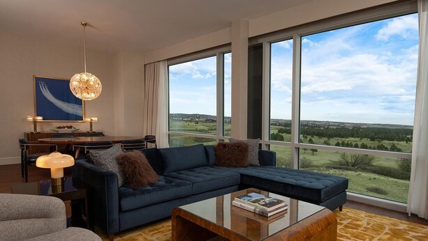 A modern living room with a sectional sofa, a coffee table, and a dining area with a chandelier.