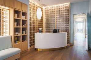 A reception area with a white reception desk, wooden shelving, and a seating area. - Hotel Polaris (Colorado Springs)