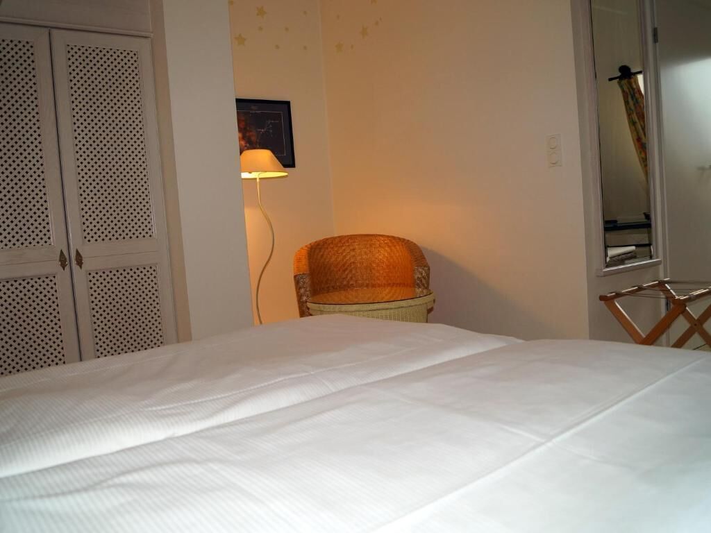 A bedroom with a bed, a chair, a lamp, and a wardrobe.