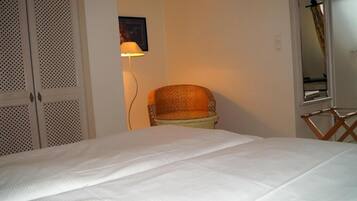 A bedroom with a bed, a chair, a lamp, and a wardrobe.