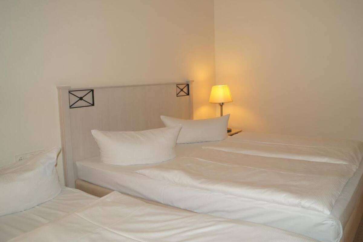A hotel room with a bed, a nightstand, and a lamp.