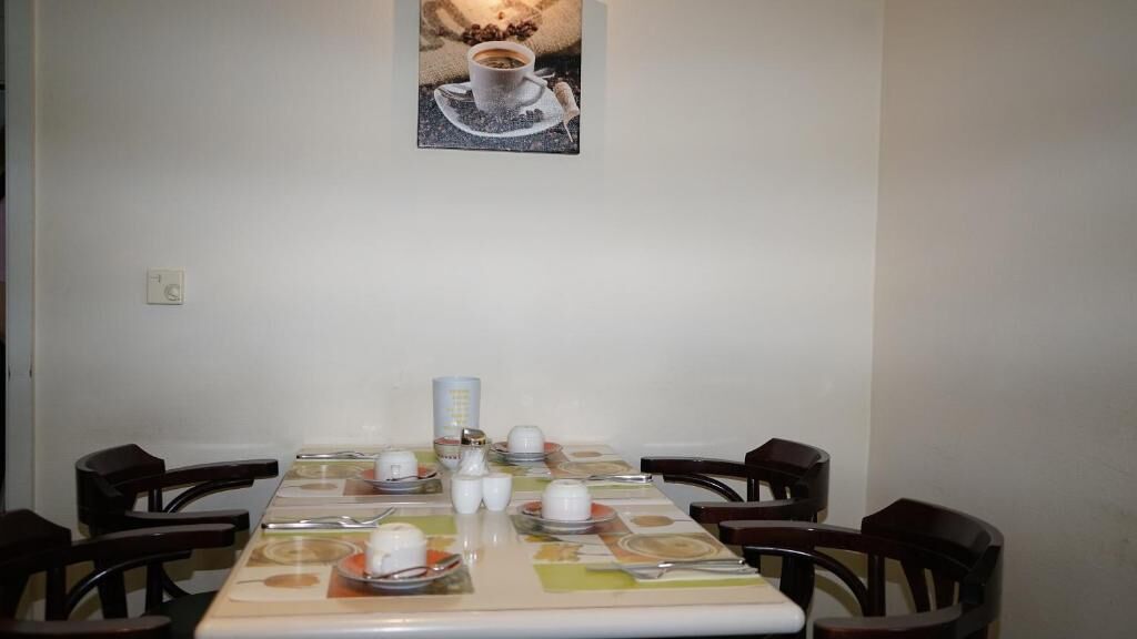 Una mesa de comedor con platos, tazas y cubiertos, rodeada de sillas.