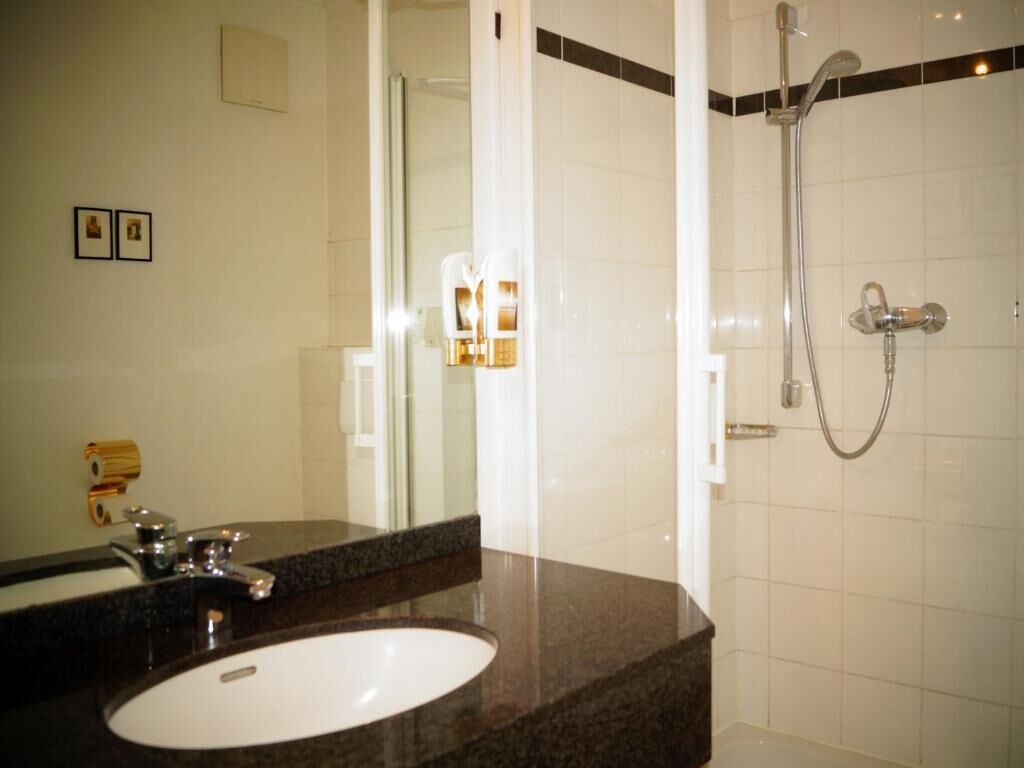 Une salle de bain avec un lavabo, un miroir et une douche.