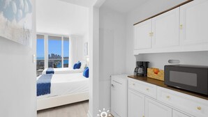 A hotel room with a bed, a kitchenette, and a view of the city. - Beautiful Studio, Amazing View Balcony (Hallandale Beach)