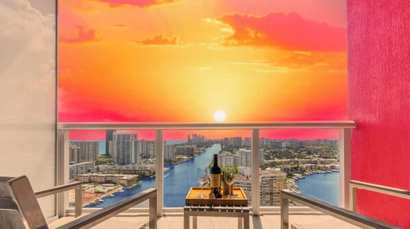 A balcony with a sunset view, a bottle of wine, and a tray.