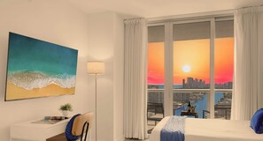 A hotel room with a bed, a desk, a chair, a lamp, a painting, and a large window with a city view.