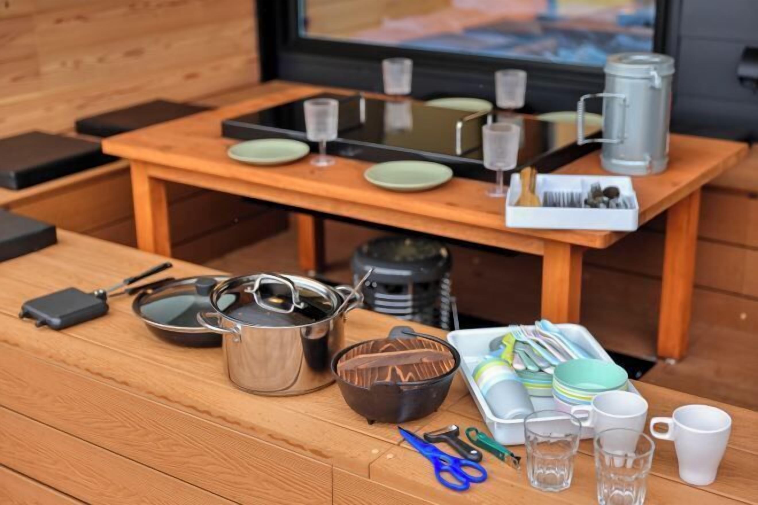 Una mesa de madera con utensilios de cocina, como ollas, sartenes y utensilios, y una ventana con vistas.