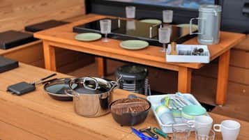 A wooden table with kitchenware, including pots, pans, and utensils, and a window with a view.