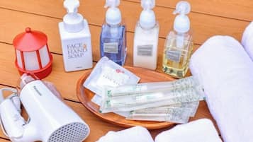 A wooden surface with various toiletries including face soap, shampoo, conditioner, and a hairdryer.
