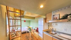A compact kitchen with a wooden bench, a small table, and a refrigerator. - Piilo asobi＆stay (Yamanakako)