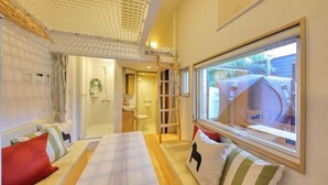 A hotel room with a bed, a window with a view, a shower area, and a small bathroom. - Piilo asobi＆stay (Yamanakako)