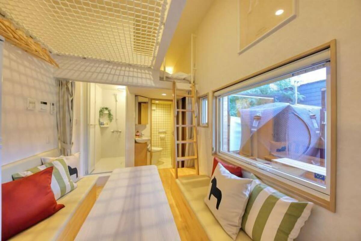 A hotel room with a bed, a window with a view, a shower area, and a small bathroom.
