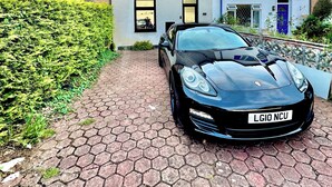 Une voiture de sport noire était garée sur une allée pavée devant une rangée de maisons aux styles architecturaux différents.