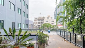 A modern building with multiple floors, large windows, and a balcony area with potted plants.
