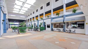A spacious indoor atrium with multiple levels, featuring a cafe and a restaurant on the ground floor.