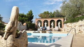 A swimming pool with stone statues and a stone swan decoration.