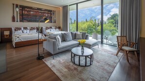 Une chambre d’hôtel moderne, dotée d’un grand lit, d’un canapé, d’une table basse et offrant une vue sur l’extérieur.