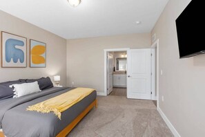 Un dormitorio con cama, televisor y puerta que da a un baño.