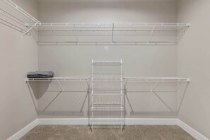 A walk-in closet with metal shelving units and a hanging rod.