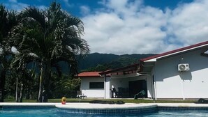 A swimming pool with clear blue water, surrounded by palm trees and a white building with a red roof. - 3 bedrooms. Large pool. Gated. Private. Ojochal. (Ojochal)