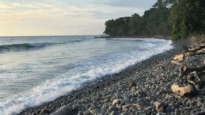 A pebbled beach with waves, a forested cliff, and a clear sky. - 3 bedrooms. Large pool. Gated. Private. Ojochal. (Ojochal)