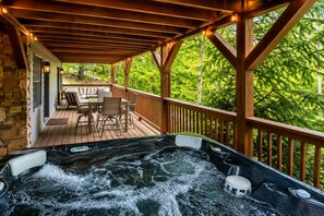 A hot tub with a wooden deck and outdoor seating area. - Beautiful 4-bedroom, 3-bathroom Mountain Getaway - Hot Tub + Mountain Views! (Mars Hill)