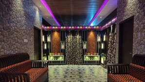 A lobby with stone walls, a pebbled floor, and two sofas. - Mary Land  Homestay - A  "Private Pool Villa" Near Trivandrum Airport and Beach. (Thiruvananthapuram)