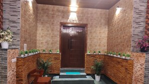 A reception area with a wooden bench seating, a reception desk, and a door with a wooden frame. - Mary Land  Homestay - A  "Private Pool Villa" Near Trivandrum Airport and Beach. (Thiruvananthapuram)