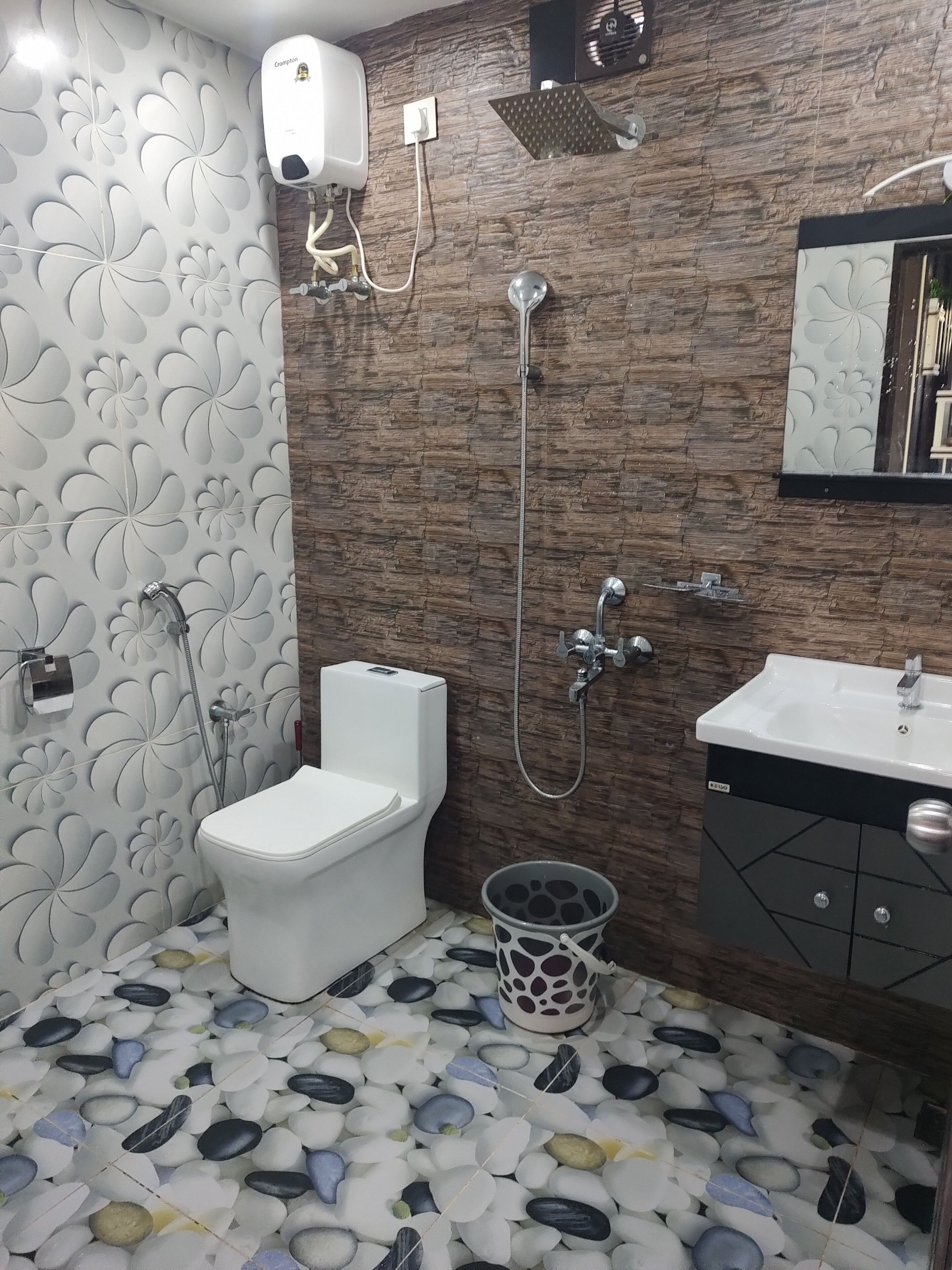 A bathroom with a toilet, shower, sink, and decorative wall tiles.