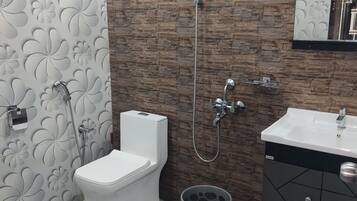 A bathroom with a toilet, shower, sink, and decorative wall tiles.
