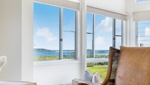 Een kamer met uitzicht op zee, een rieten stoel en een bank.