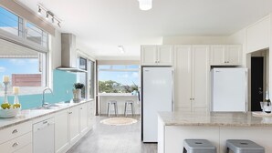 Een moderne keuken met witte kasten, een groot eiland met krukken, en uitzicht naar buiten.