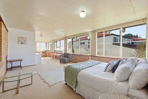 Une chambre à coucher avec un lit, une table en verre, un banc et une chaise.