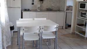 A kitchen with a white table and chairs, a clock, a stove, and a microwave.