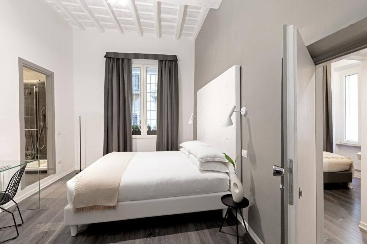 A modern bedroom with a large bed, a glass shower enclosure, and a view of the outdoors.