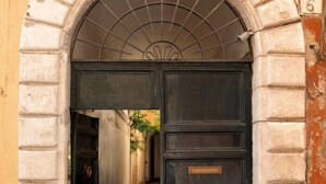 A large, dark wooden door with a metal arch above it, set in a stone wall. - N-SPACE MODERN GUEST ROOMS (Rome)