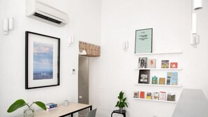 A modern office space with a desk, chairs, a framed picture, a small plant, and a bookshelf with books. - N-SPACE MODERN GUEST ROOMS (Rome)