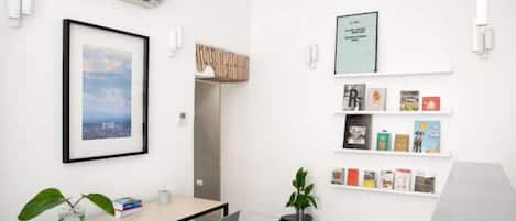 Een moderne kantoorruimte met een bureau, stoelen, een ingelijst beeld, een kleine plant en een boekenkast vol boeken.