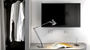 A modern room with a desk, a flat-screen TV, a desk lamp, and a bookshelf. - N-SPACE MODERN GUEST ROOMS (Rome)