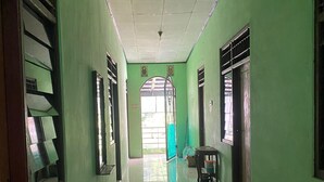 A hallway with green walls, a tiled floor, and a bench. - Hotel O Kost Bunda Syariah (Bekasi)