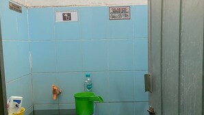 A small, basic bathroom with a toilet, a green bucket, a water bottle, and a broom. - Hotel O Kost Bunda Syariah (Bekasi)