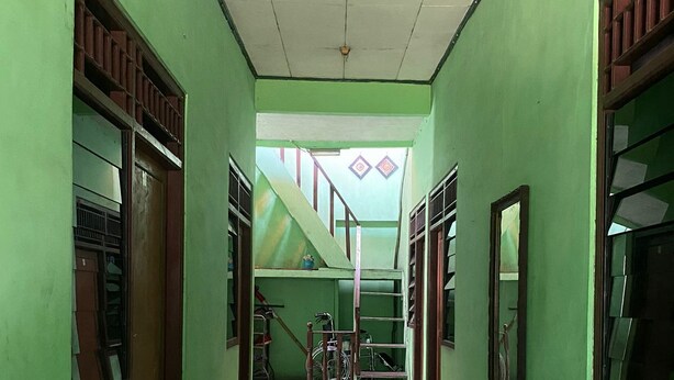 A hallway with green walls, a tiled floor, and a staircase leading to an upper level. - Hotel O Kost Bunda Syariah (Bekasi)