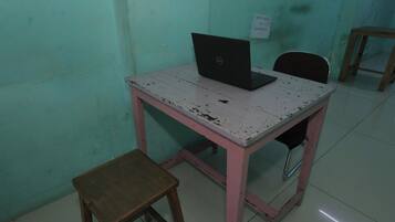 Una habitación pequeña con un escritorio, una computadora portátil y una silla.