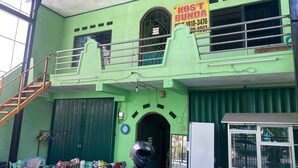 A green building with a 'KOST BUNDA' sign, a staircase, and a motorcycle parked in front. - Hotel O Kost Bunda Syariah (Bekasi)