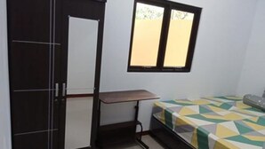 A small room with a bed, a desk, and a wardrobe. - Hotel O Kost Bunda Syariah (Bekasi)