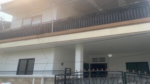 A two-story building with a balcony on the upper floor, a gated entrance, and visible power lines.