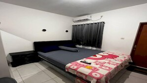 A bedroom with a single bed, a nightstand, a dresser, a window with curtains, and an air conditioning unit.